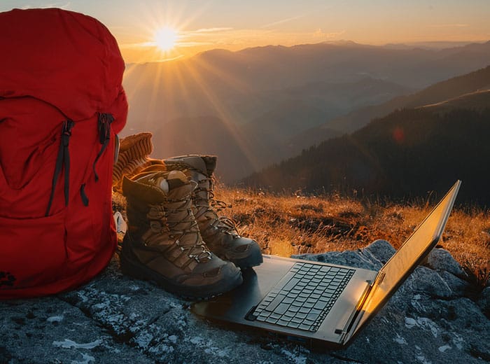 Backpack and boots resting at the top of the peak near a laptop after a job well done