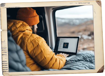 Man with orange jacket sitting in vehicle working on computer